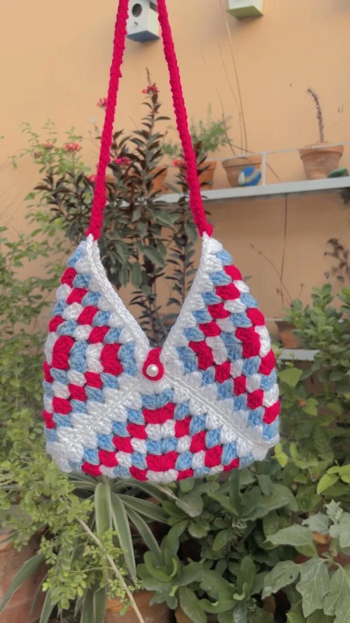 Red, pale blue and white crochet shoulder bag with a red strap